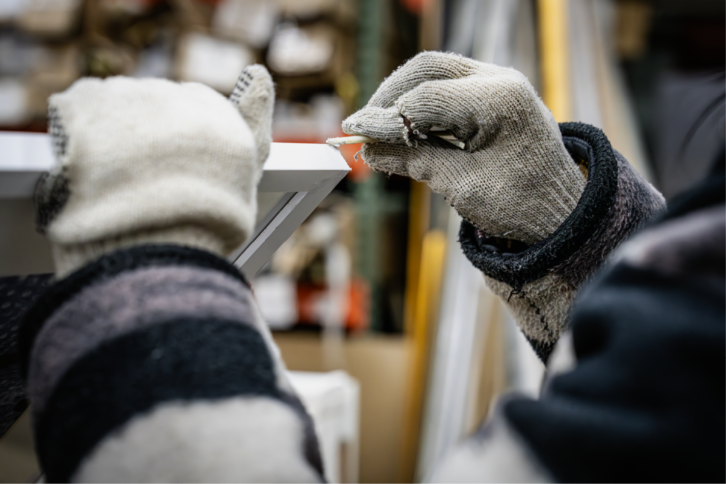 Worker sanding edge, gloved hands, workshop background